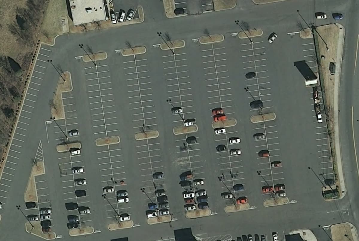Aerial view straight down on a retail parking field, 2010: Striped, the pavement gray. The 2010 flight is coarser than the others.