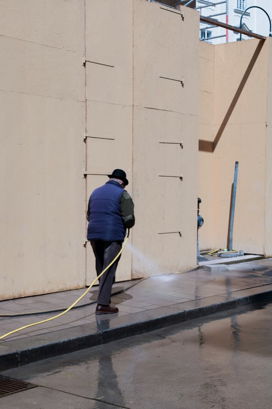 A contractor washing the exterior wall of a commercial building, the kind of scheduled property work a recurring service agreement covers