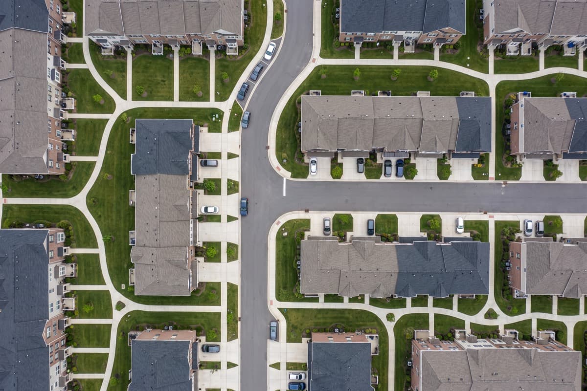 Aerial view of a network of concrete sidewalks running between townhouse buildings in an HOA community